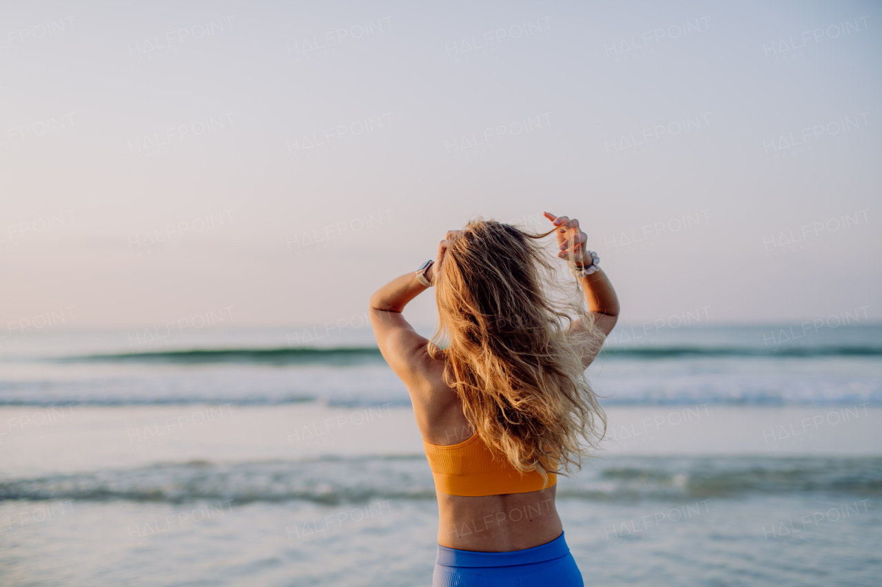 Rear view of young sportive woman at the beach.