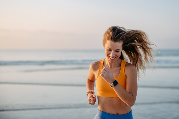 Young woman running at the beach, morning routine and healthy lifestyle concept.