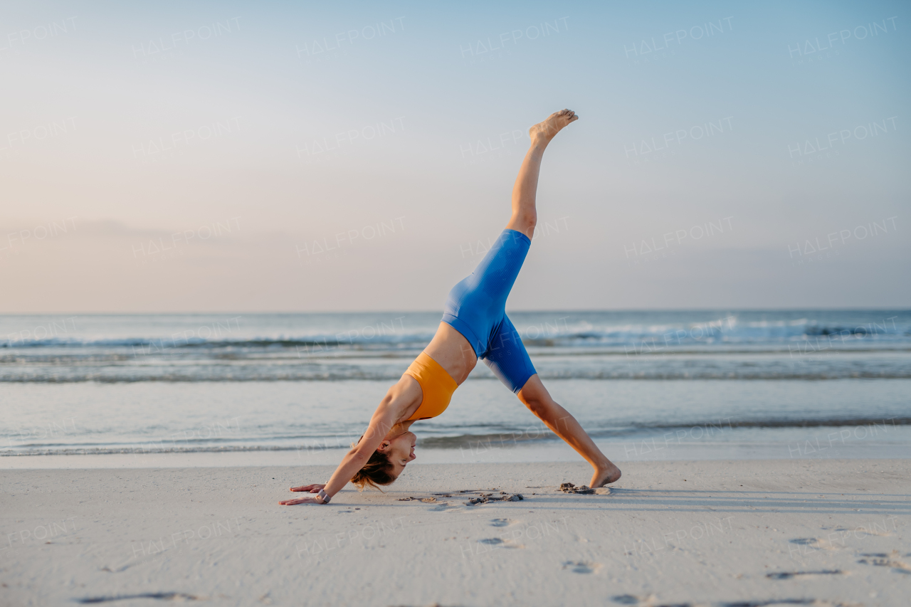 Young woman taking exercises at the beach, morning routine and healthy lifestyle concept.