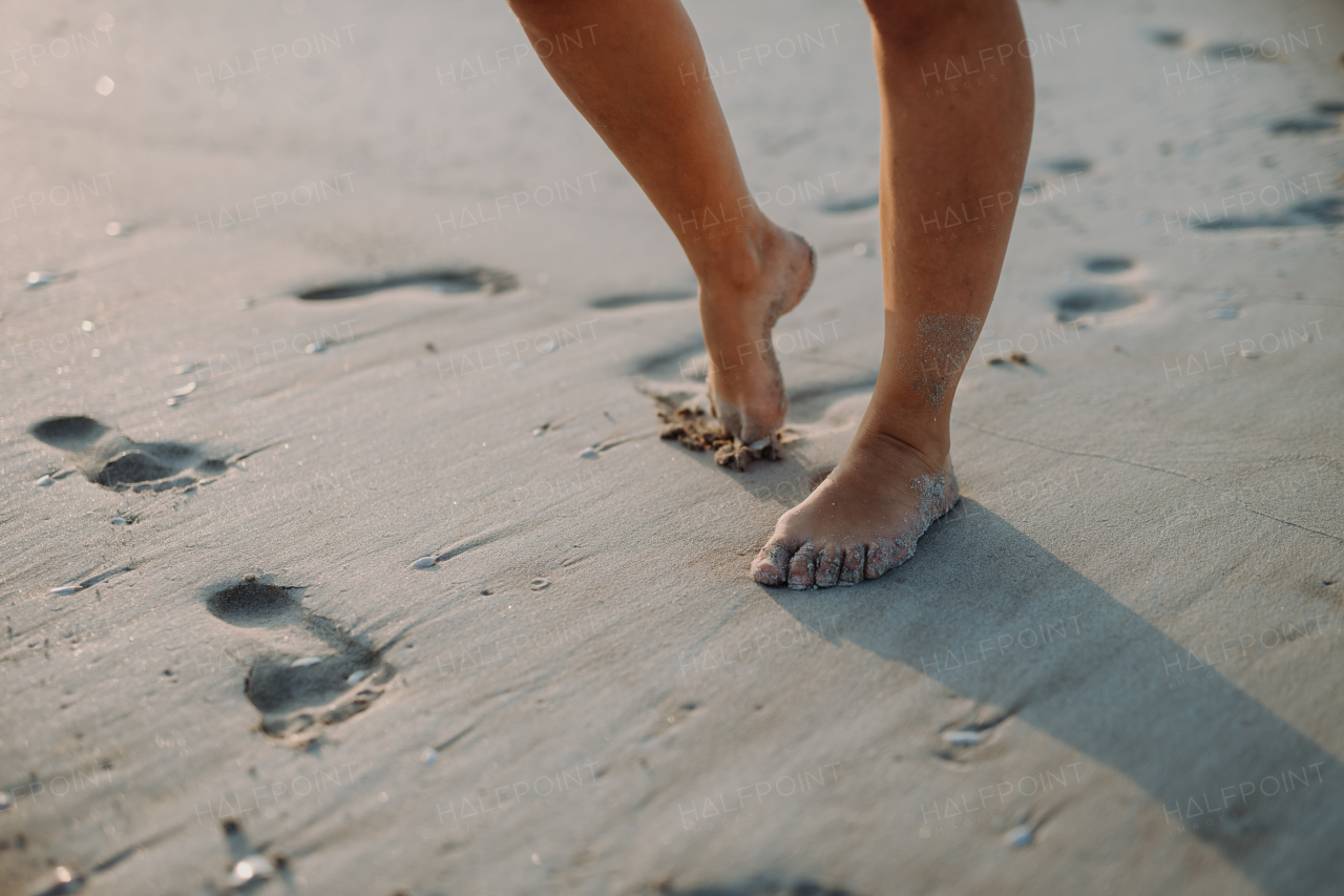 Close-up of childs feet in a sand, at sea.