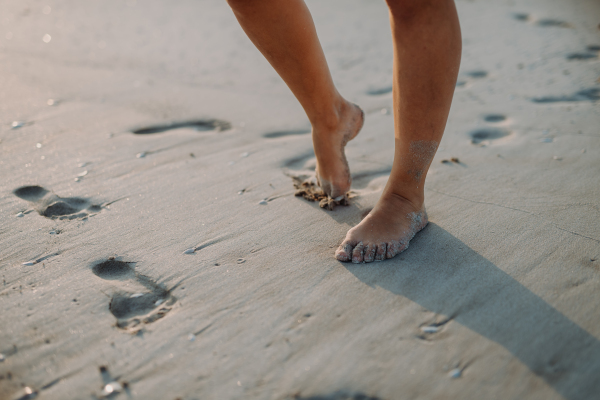 Close-up of childs feet in a sand, at sea.