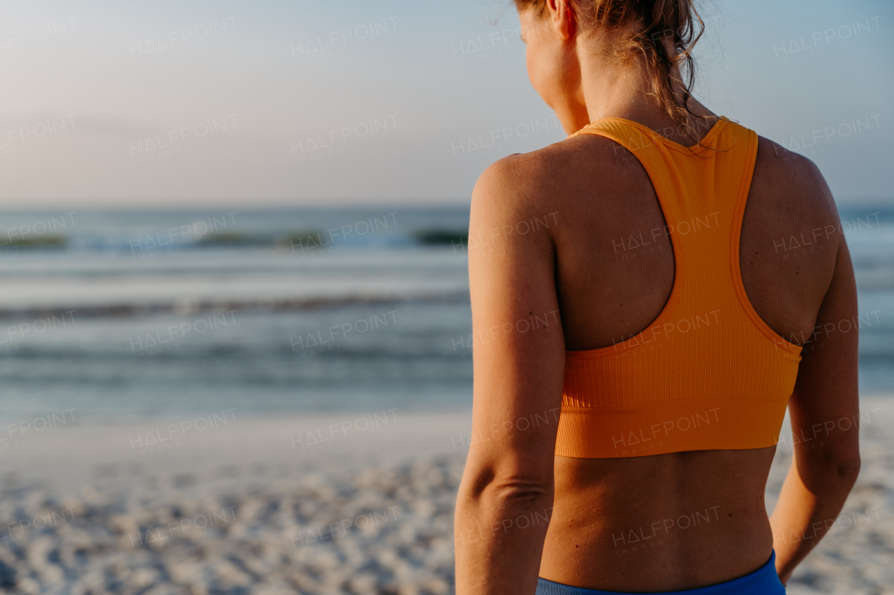 Rear view of young sportive woman at the beach.