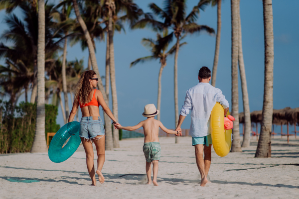 Happy family with little child enjoying time at vaccation in exotic country, rear view.