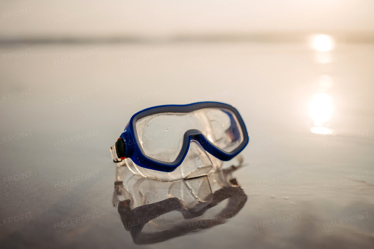 Close-up of snorkeling goggles on a beach.