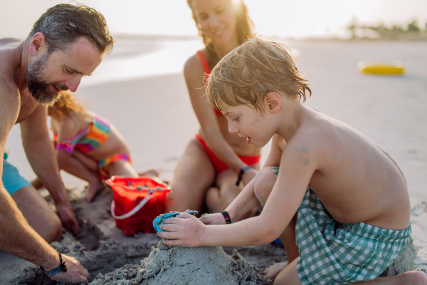 Happy family with little kids enjoying time at the sea in exotic country,building sand castle.