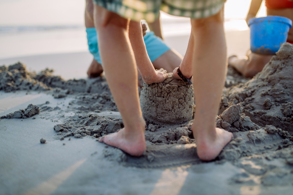 Close-up of children playing on the beach, building a sand castle.