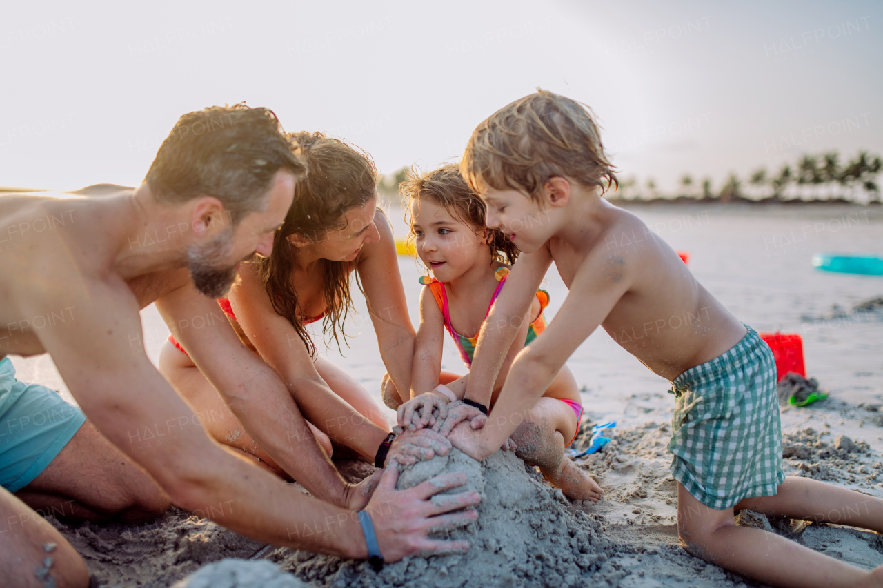 Happy family with little kids enjoying time at the sea in exotic country,building sand castle.