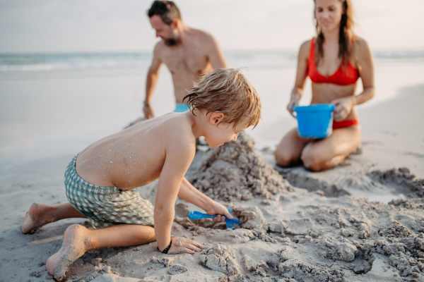 Happy family with little kids enjoying time at the sea in exotic country,building sand castle.