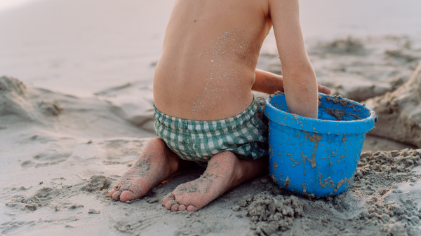 Little boy playing on the beach, building a sand castle.