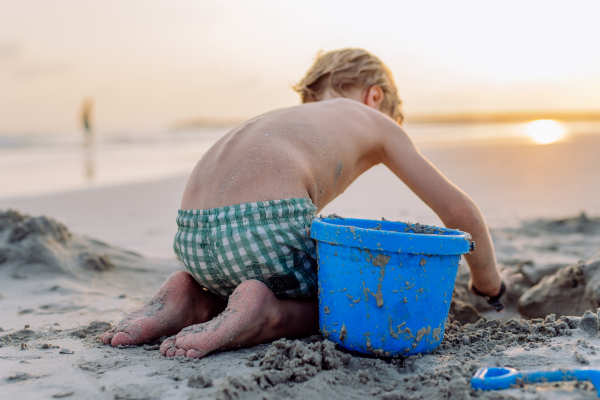 Little boy playing on the beach, building a sand castle.