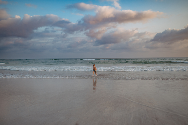 Little boy in swimsuit running out of sea, enjoying summer holiday.