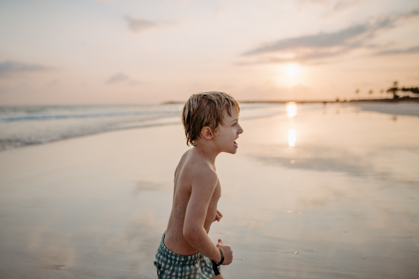 Little boy in swimsuit running out of sea, enjoying summer holiday.