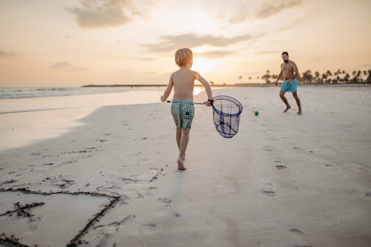 Father with his son plaing football on a beach.