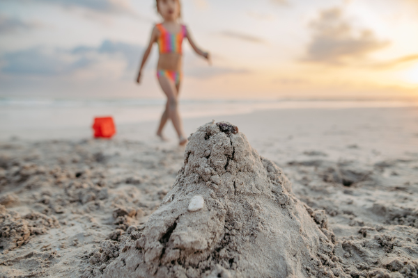 Little girl playing on the beach, building a sand castle.