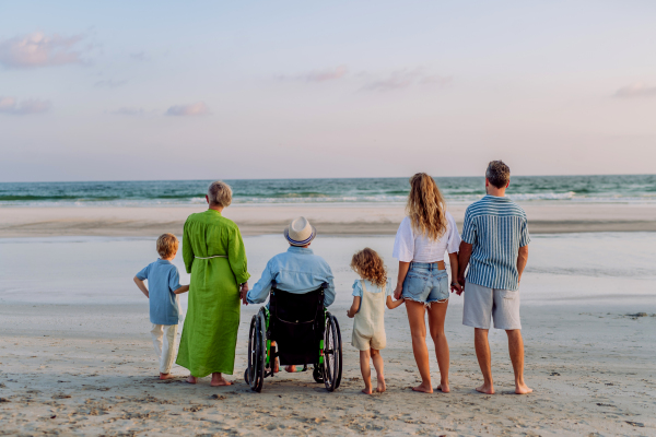 Rear view of three geneartions family with little kids enjoying time at sea in an exotic country.