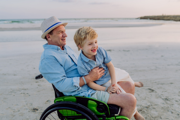 Little boy with his granfather on wheelchair, having fun and enjoying sea.