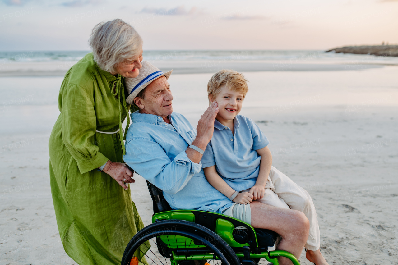 Little boy with his granfather on wheelchair, having fun and enjoying sea.