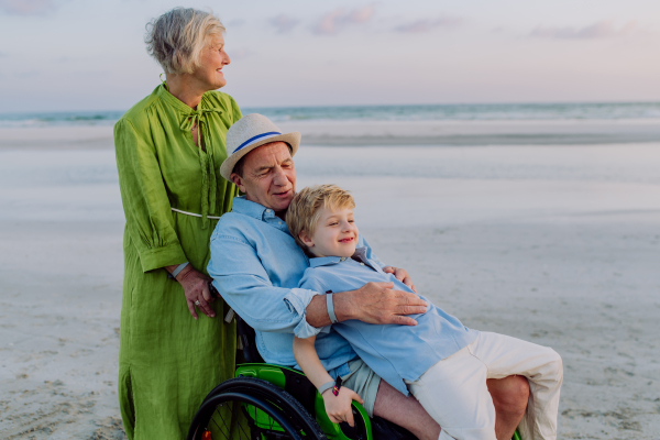 Little boy with his granfather on wheelchair, having fun and enjoying sea.