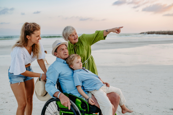 Little boy with his granfather on wheelchair, having fun and enjoying sea.