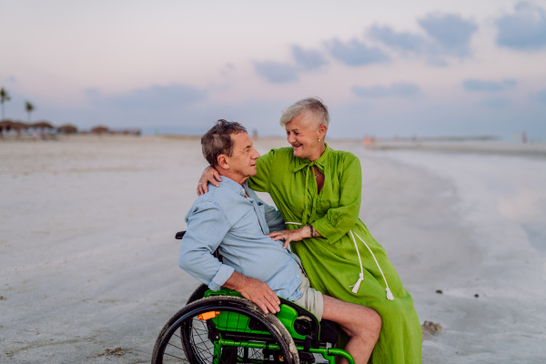 Senior man on wheelchair enjoying together time with his wife at the sea.