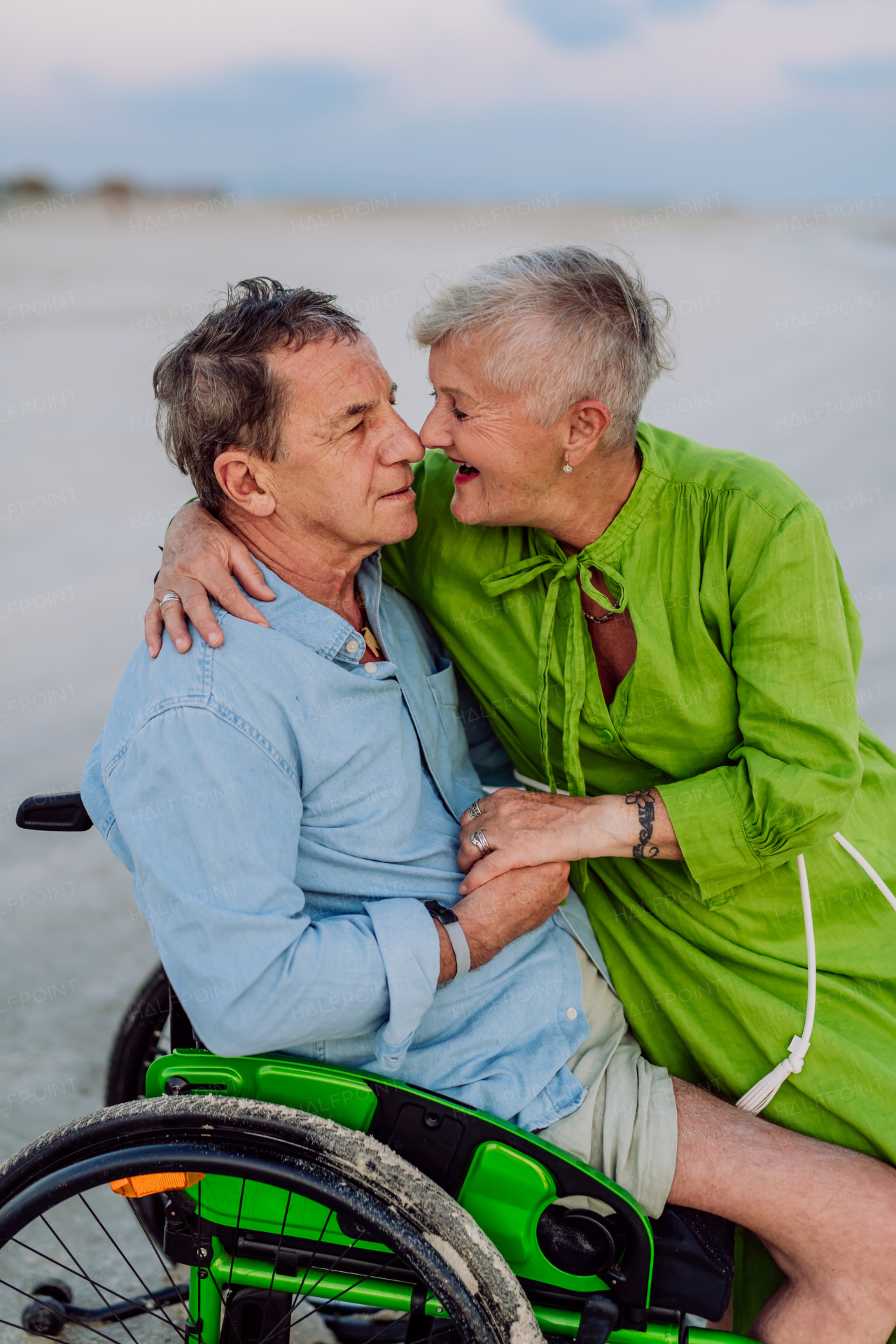 Senior man on wheelchair enjoying together time with his wife at the sea.