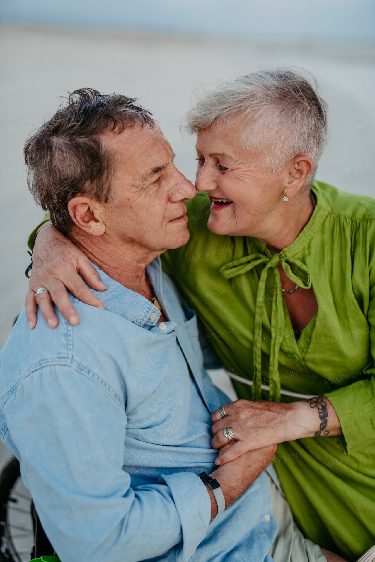 Senior man on wheelchair enjoying together time with his wife at the sea.