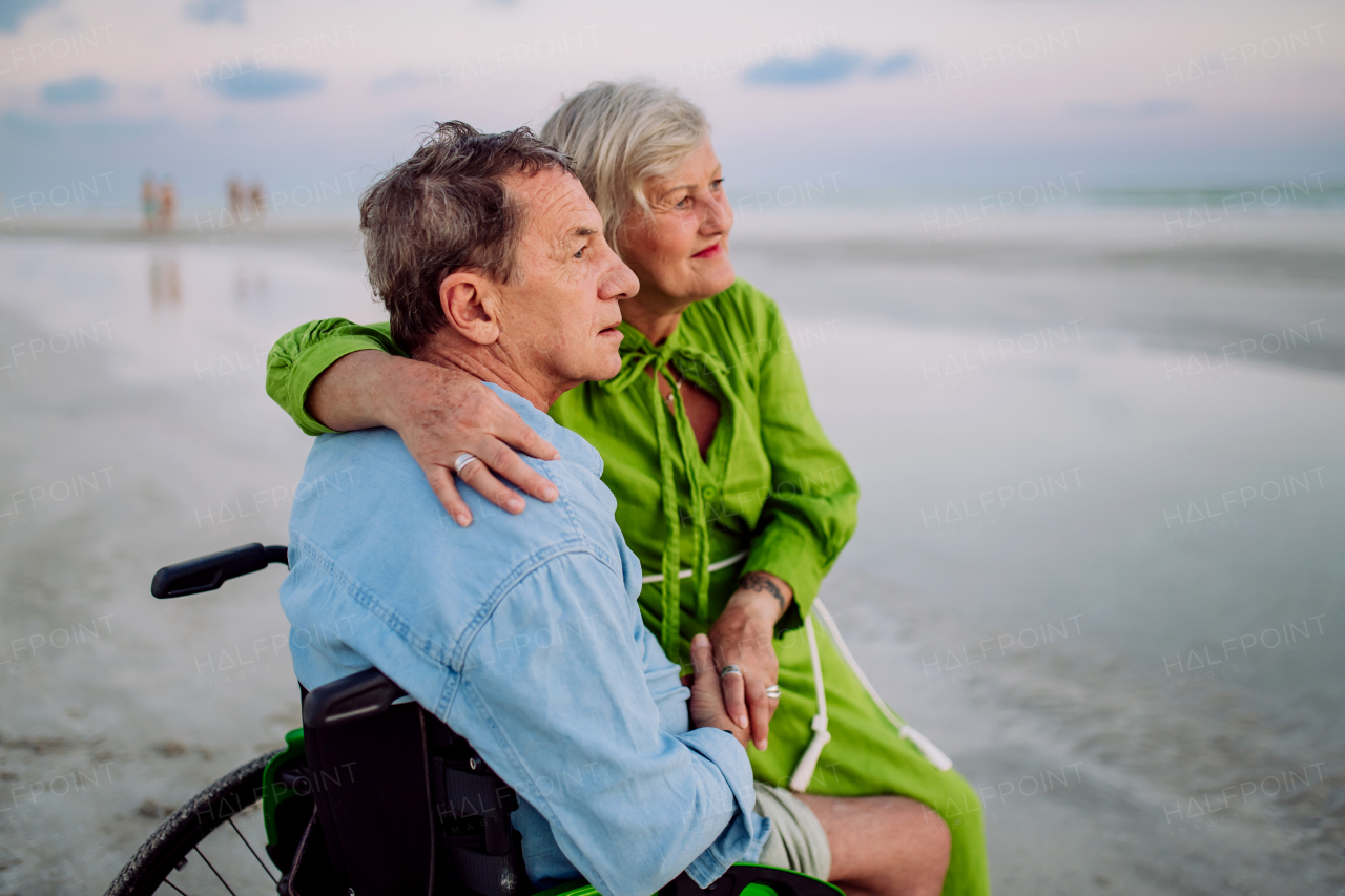 Senior man on wheelchair enjoying together time with his wife at the sea.