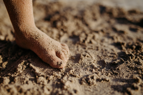 Close up of children foot in a sand.