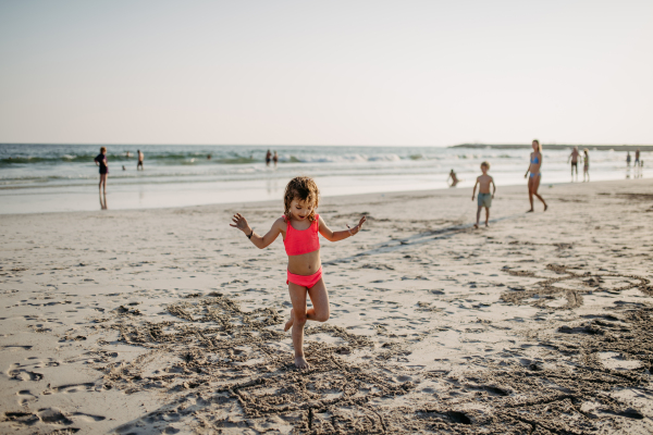 Little girl jumping on beach during summer holliday.