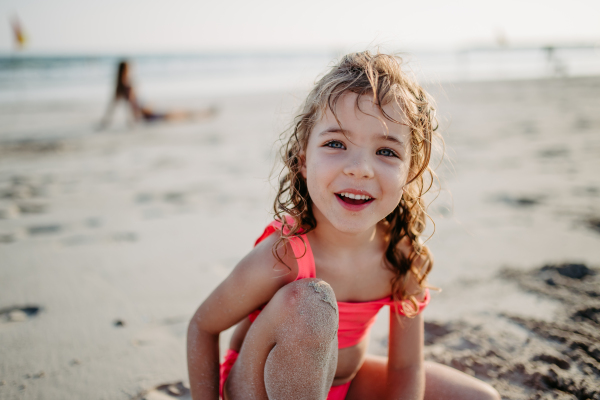 Little girl playing on the beach, digging hole in the sand.