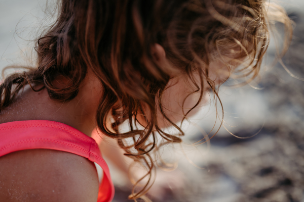 Close-up of little girl during playing on the beach, digging hole in the sand.