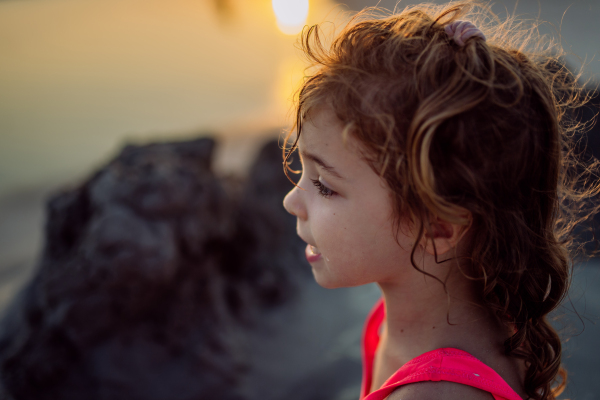 Portrait of little girl during playing on the beach, digging hole in the sand.