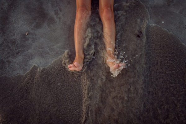 High angle view of childs legs in the ocean.