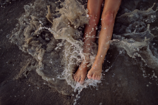 Top view of childs legs in the ocean.