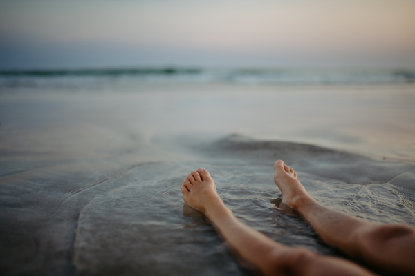 High angle view of childs legs in the ocean.