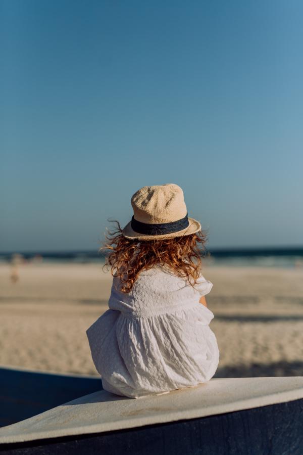 Rear view of little girl looking at the ocean.