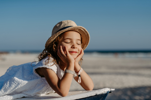 Portrait of little girl with closed eyes, at ocean.