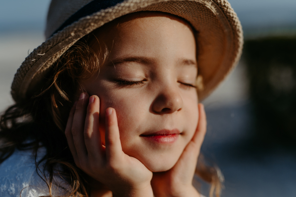 Portrait of little girl with closed eyes, at ocean.