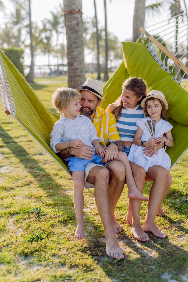 Young family with little kids enjoying their holiday in exotic country, lying in a hammock.