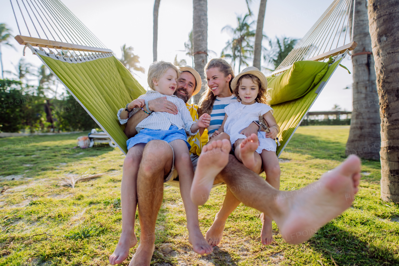 Young family with little kids enjoying their holiday in exotic country, lying in a hammock.