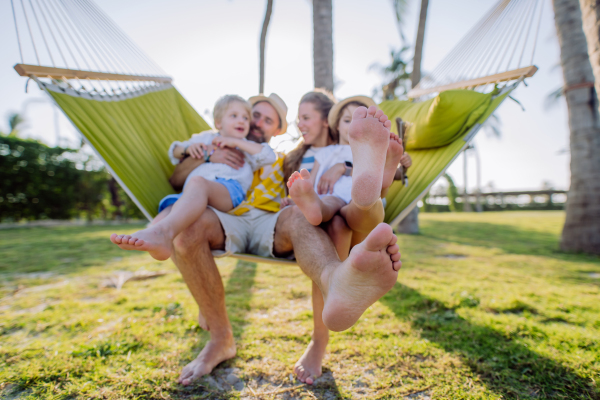 Young family with little kids enjoying their holiday in exotic country, lying in a hammock.