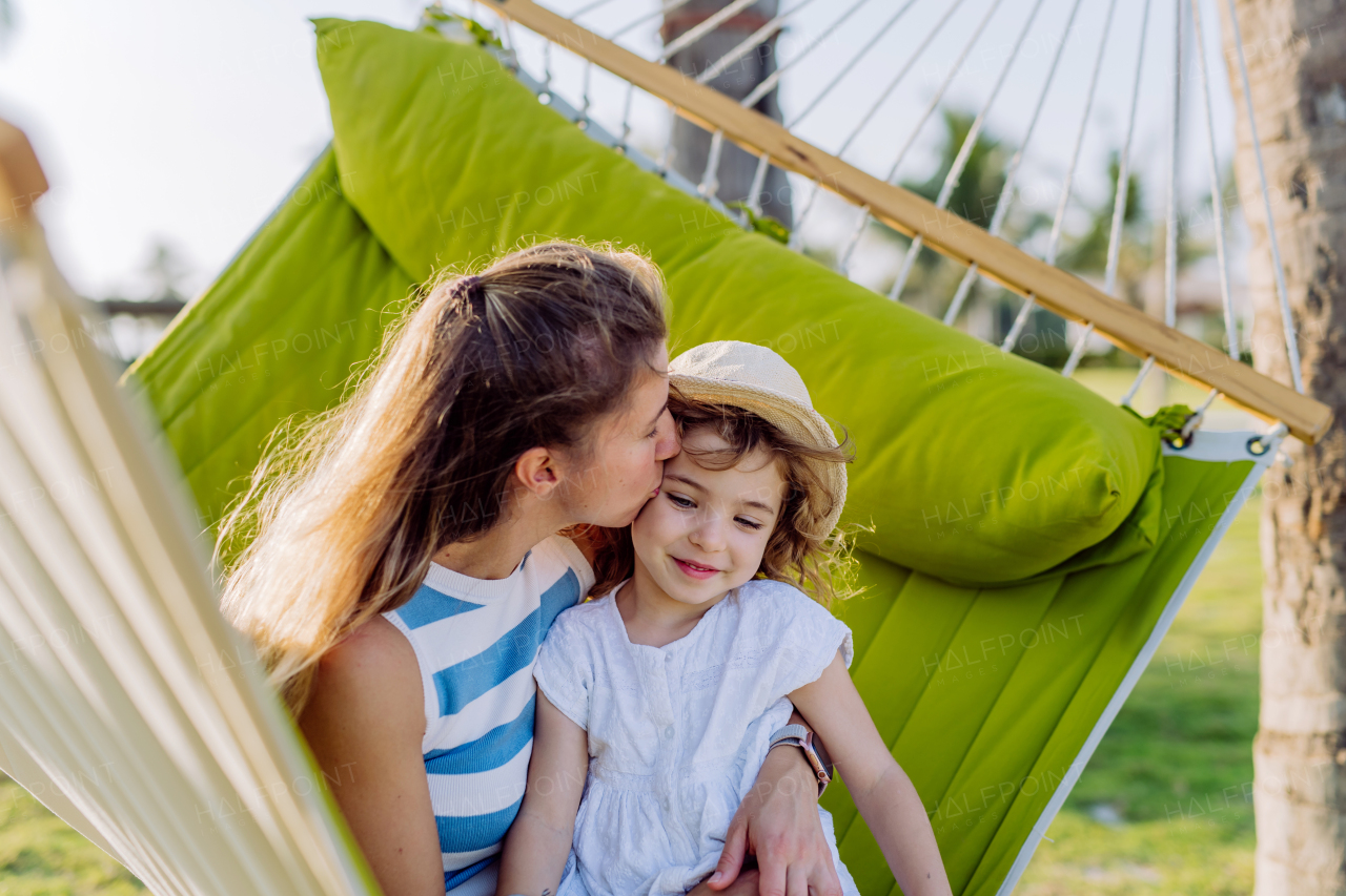 Mother with her daughter enjoying their holiday in exotic country, lying in hammock.