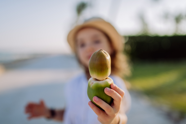 Little girl posing with an exotic fruit, enjoying time during tropical vacation.