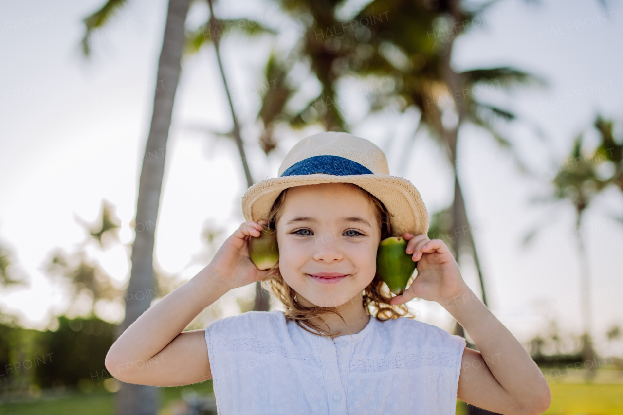 Little girl posing with an exotic fruit, enjoying time during tropical vacation.