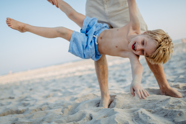 Father holding his son upside down, enjoying summer vacation and having fun.