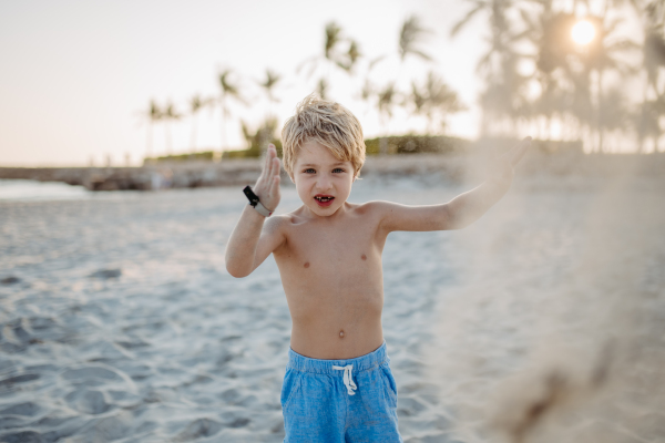 Little playful boy playing with sand on the beach.