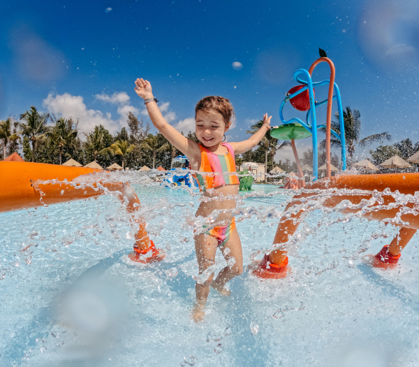 Little girl enjoying water amusement park during family holiday in exotic country.