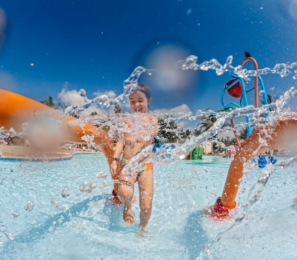 Little girl enjoying water amusement park during family holiday in exotic country.