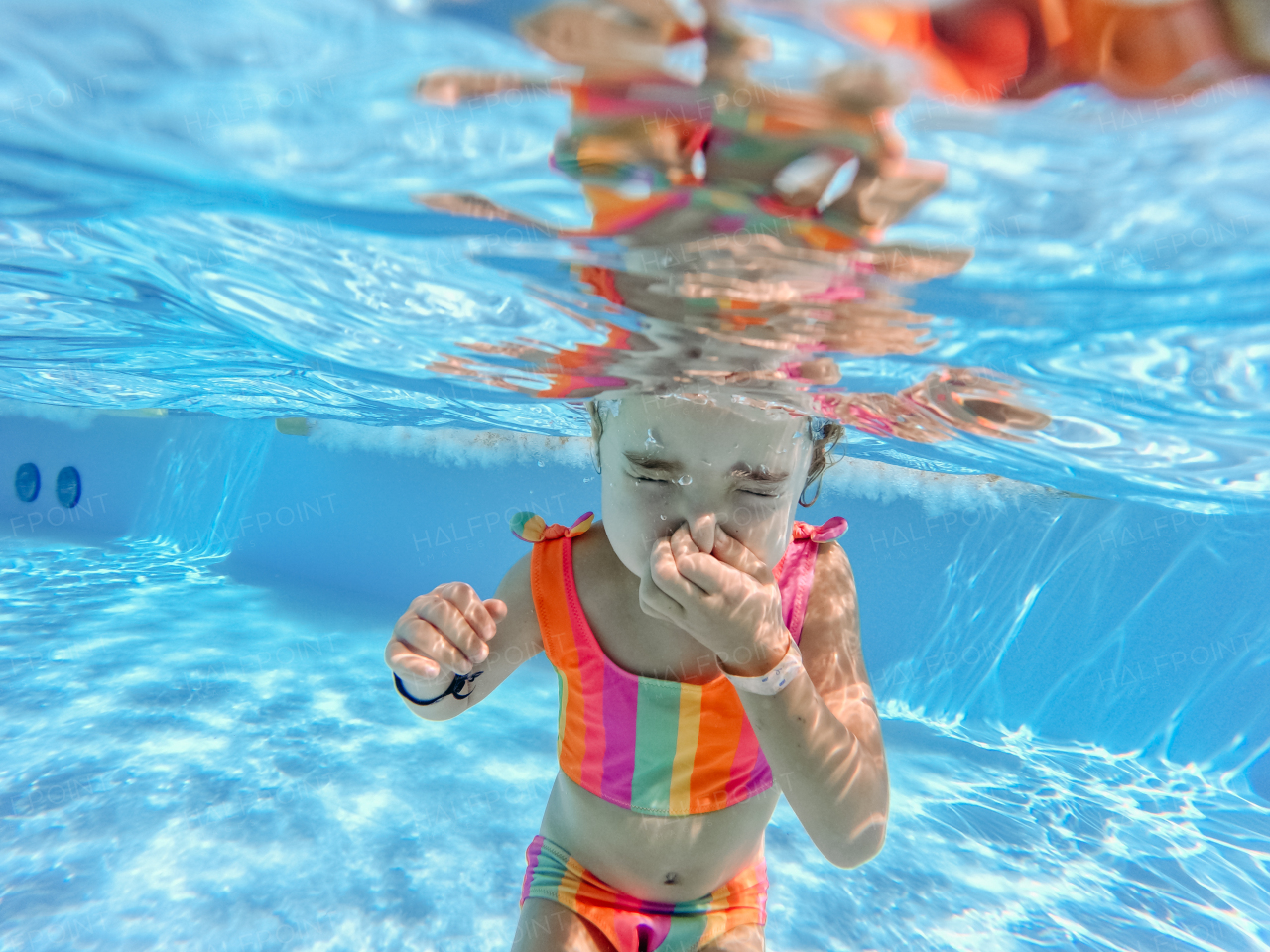 Little girl in swimsuit diving in a swimming pool.