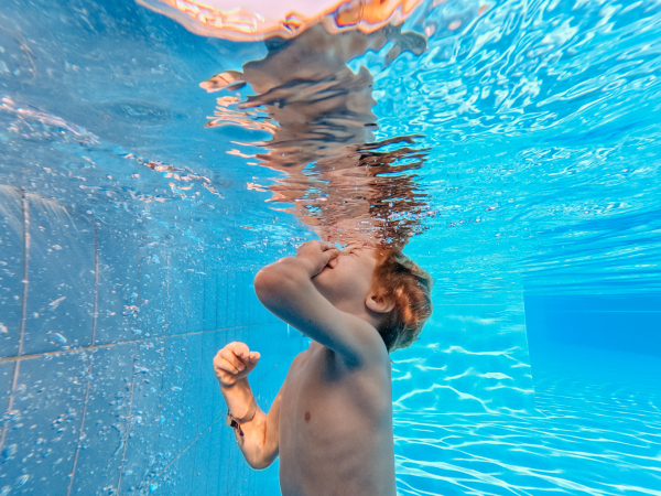 Little boy in swimsuit diving in a swimming pool.